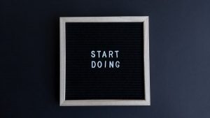 Black letter board with the motivational phrase 'Start Doing' in white text on a gray background.