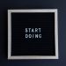 Black letter board with the motivational phrase 'Start Doing' in white text on a gray background.